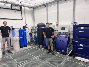 Philipp Kobler, Production and Automation Engineer, and Markus Pirchl, control systems technician, in front of the new merlin® water treatment system as well as the ORBIT WING® and CORBIT® units.